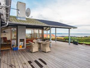 a wooden deck with a table and chairs on it at 6 person holiday home in R nde in Rønde