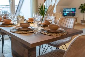 a wooden table with plates and glasses on it at Hejm Apart - Design Maisonette-Ferienwohnung "Zugspitze" in Mering