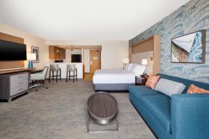 a hotel room with a bed and a blue couch at Holiday Inn Va Beach-Oceanside 21st St, an IHG Hotel in Virginia Beach