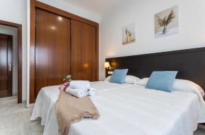 1 dormitorio con 2 camas grandes y toallas. en Acceso Sevilla Piscina Moderno Parking Gratis, en Bormujos