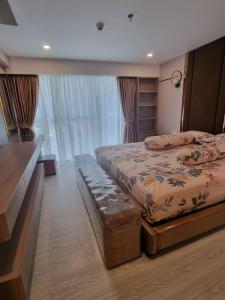 Un dormitorio con 2 camas y un banco. en Apartemen Grand Jati Junction Medan 3 Kamar en Medan