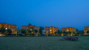 un groupe de bâtiments dans un champ la nuit dans l'établissement Anantvan Ranthambore By ShriGo Hotels, à Khilchīpur