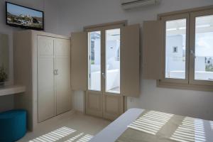 a bedroom with a bed and a cabinet and windows at Muses in Aegiali
