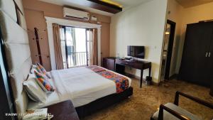 a bedroom with a bed and a desk and a television at Crystal Paark Inn By Blu Orchid Group in Mysore