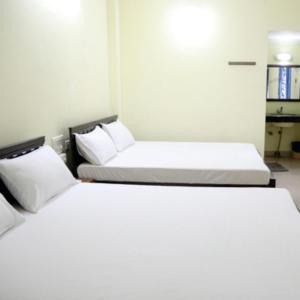 two beds in a room with white sheets and pillows at Geetha Residency in Kanchipuram