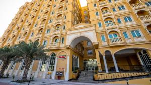 um grande edifício amarelo com palmeiras em frente em Somerset Al Mansoura Doha em Doha