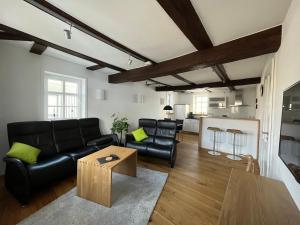 a living room with black leather furniture and a kitchen at Ferienwohnung Ederblick in Wabern
