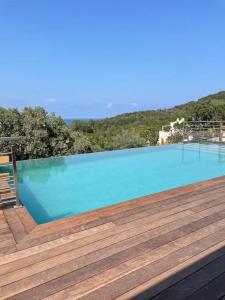 une grande piscine bleue avec une terrasse en bois dans l'établissement Villa neuve avec grande piscine chauffée vue mer, à Conca