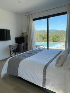 - une chambre avec un grand lit et une grande fenêtre dans l'établissement Villa neuve avec grande piscine chauffée vue mer, à Conca