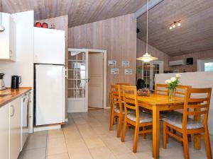 una cucina con tavolo in legno, sedie e frigorifero di 8 person holiday home in Oksb l a Oksbøl