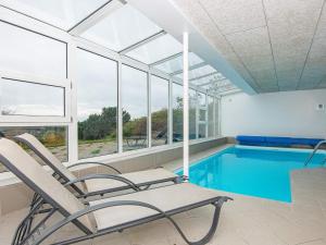 a room with a swimming pool and two chairs and a swimming pool at 8 person holiday home in Ebeltoft in Ebeltoft