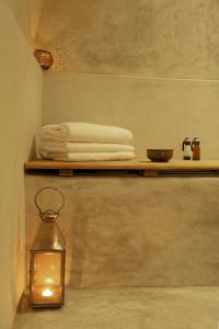 a bathroom with a shelf with towels and a lantern at Riad RK Suites & Spa in Marrakesh