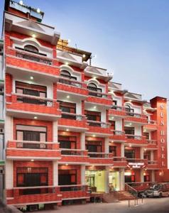 a large red and white building with a parking lot at Sun Hotel-Haridwar in Haridwār