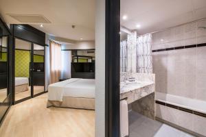 a bedroom with a bed and a bathroom with a tub at Motel Punt 14 in Gavà