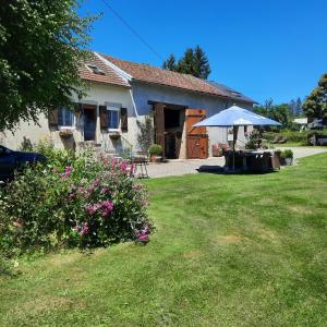 una casa con una mesa y una sombrilla en un patio en Chambre d'hôte Le Châtaignier, en Planchez