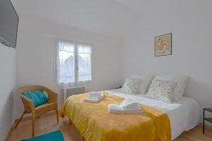 een witte slaapkamer met een bed en een stoel bij La Bodeguita : Roissy CDG, Parc Astérix, Parc Des Expositions in Marly-la-Ville