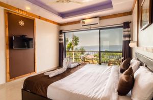 a bedroom with a large bed with a large window at Saga Resort in Mahabaleshwar