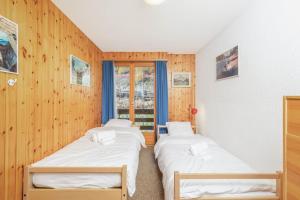 3 Betten in einem Zimmer mit Holzwänden und einem Fenster in der Unterkunft App Les Lupins 16 in Riddes