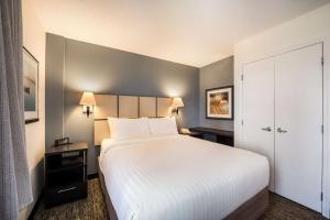 a hotel room with a large bed with white sheets at Sonesta Simply Suites Silicon Valley Santa Clara in Santa Clara