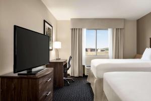 a hotel room with two beds and a flat screen tv at Baymont by Wyndham Rawlins in Rawlins