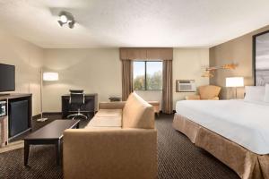 a hotel room with a large bed and a couch at Super 8 by Wyndham Lincoln North in Lincoln