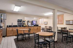 a restaurant with tables and chairs and a kitchen at Super 8 by Wyndham Lincoln North in Lincoln