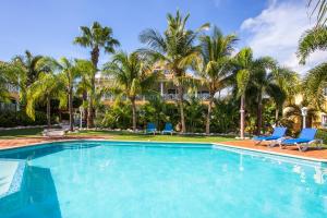 a swimming pool with blue chairs and palm trees at Tropicana Palm Penthouse Jan Thiel, Willemstad Curacao in Jan Thiel