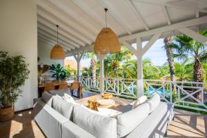 una sala de estar al aire libre con muebles blancos y palmeras. en Tropicana Palm Penthouse Jan Thiel, Willemstad Curacao en Jan Thiel