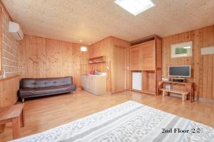 ein Wohnzimmer mit einem Sofa und einem TV in der Unterkunft Healing Camp Yesone in Gangneung