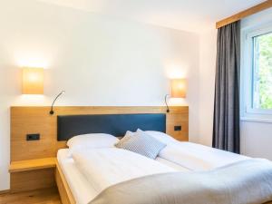 2 Betten in einem Schlafzimmer mit 2 Lampen an der Wand in der Unterkunft Landal Resort Maria Alm in Maria Alm am Steinernen Meer