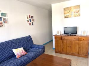 sala de estar con sofá azul y TV de pantalla plana en APARTAMENTO AZUL, en Orzola
