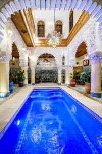 a large swimming pool in a building with a ceiling at Riad Rcif Alif Suite & SPA in Fez