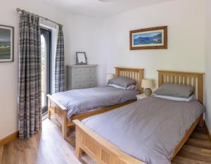 two twin beds in a room with a window at Kinlochlaich Tree House in Appin