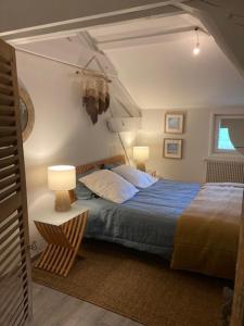 a bedroom with a bed and a table with a lamp at Les CHAMBRES des EAUX in Sarcey