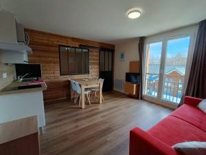 a living room with a red couch and a table at Fleurs des Alpes in Les Déserts