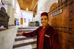 Un uomo in piedi in un palazzo con la mano fuori di Riad Rcif Alif Suite & SPA a Fes