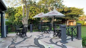 a patio with tables and chairs and an umbrella at Umdlalo Lodge in Port Shepstone