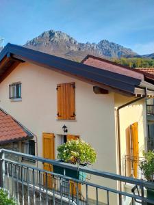 a house with a balcony with a mountain in the background at Cozy Home Maison Cascina Amélie in Abbadia Lariana