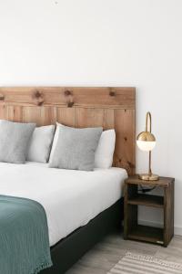 a bed with a wooden headboard and a lamp on a table at Swell House in Ferrel