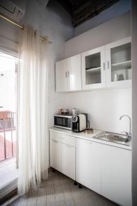 a kitchen with white cabinets and a microwave and a window at LUDUS ROOMS in Rome