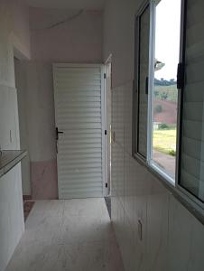 baño con puerta blanca y ventana en Recanto das Videiras, en Maria da Fé