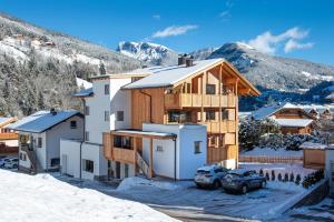 a house in the snow with mountains in the background at Apartments Bea in Ortisei