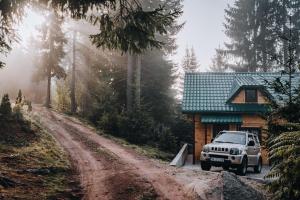 ein Jeep, der vor einem Haus auf einer unbefestigten Straße parkt in der Unterkunft Vilovi Botić in Nova Varoš