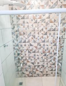 a shower with a mosaic tile wall in a bathroom at Acqua Flats Jaguariúna in Jaguariúna
