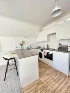 una cocina blanca con encimera y taburete. en Four Oaks en Bournemouth
