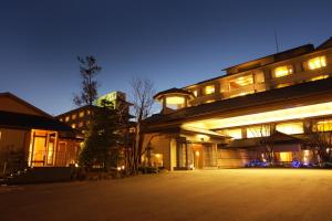 un grand bâtiment avec des lumières allumées la nuit dans l'établissement Yumotoya, à Niigata