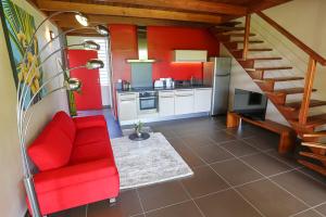uma sala de estar com um sofá vermelho e uma cozinha em Résidence HIBISCUS 5 étoiles em Caiena