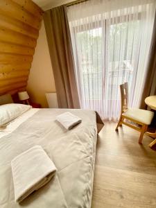 a bedroom with a bed and a chair and a window at Gościniec w Zakopanem in Zakopane +15 photos