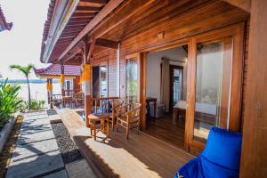 Un balcón de una casa con una cama y sillas en Nusa Veranda Sunset Villas & Restaurant, en Nusa Lembongan