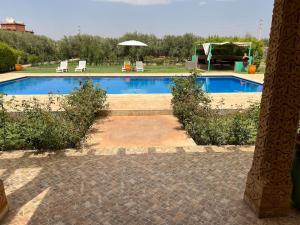 a swimming pool with two chairs and an umbrella at Luxury villa with a pool for your family getaway in Marrakesh